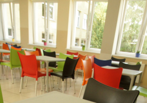 Odmienione miejsce do spożywania obiadów z kolorowymi krzesłami i stołami.